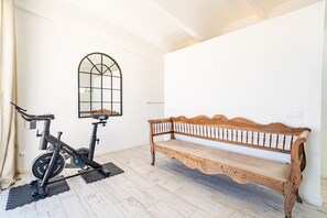 A room with a wooden bench, a bicycle, and a wall-mounted mirror. - VILLA OASIS TERRA BLANCA (Palma de Mallorca)