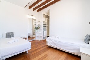 A modern bedroom with two beds, wooden flooring, a walk-in closet, and a mirror. - VILLA OASIS TERRA BLANCA (Palma de Mallorca)