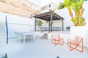 A patio area with a table and chairs, a small seating area with a bench, and a plant. - VILLA OASIS TERRA BLANCA (Palma de Mallorca)