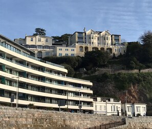 Un hôtel à plusieurs étages, doté d’un design moderne, situé sur une colline et offrant une vue sur la mer.