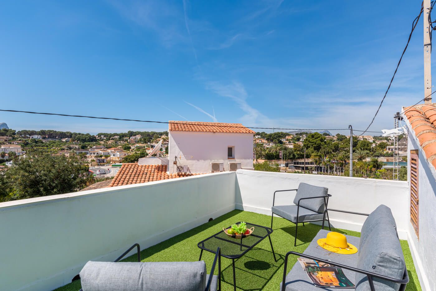 Una terrazza sul tetto con vista su una cittadina, un piccolo edificio bianco e mobili da esterno.