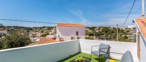 Una terrazza sul tetto con vista su una cittadina, un piccolo edificio bianco e mobili da esterno.