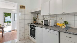 Ett modernt kök med vita skåp, en inbyggd ugn, en mikrovågsugn och en bänkskiva i granit.