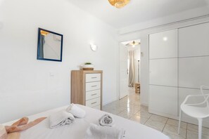Een moderne slaapkamer met een bed, een dressoir, een stoel en een inloopkast.