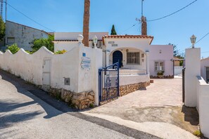 Een wit gebouw met een pannendak, een stenen muur en een blauw hek. Op de muur staat een bord met de tekst 'BILLER SPAIN'.