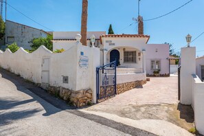 Un cancello chiuso all'ingresso di un edificio con un muro in pietra, un cancello blu e un cartello che indica un'attività commerciale denominata 'BILLER SPAIN'.