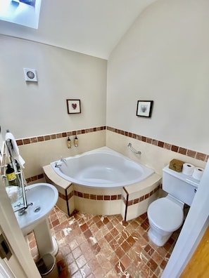 A bathroom with a bathtub, sink, toilet, and a shower area.