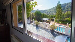 A balcony with a view of a mountainous landscape, a tiled floor, and a statue.