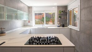 A modern kitchen with a gas stove, a large window, and a view of the garden.