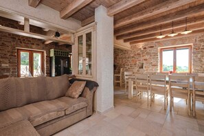 Ein gemütlicher Wohnbereich mit einer Couch, einem Esstisch mit Stühlen und einer Küchenzeile mit Schränken und einem Kühlschrank.