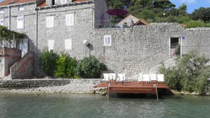 A stone building with a balcony overlooking a body of water.
