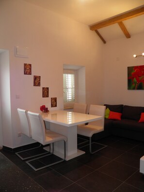 Un salon moderne avec une table à manger, des chaises blanches, un canapé et une fenêtre.