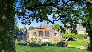 A stone house with a grassy yard and a swing.