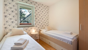Une chambre avec deux lits, une fenêtre donnant sur un beau paysage et une table de chevet avec une lampe.
