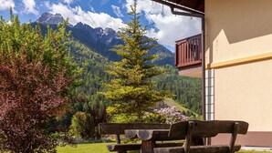 Un banc en bois avec une table, situé dans un jardin offrant une vue sur la montagne.