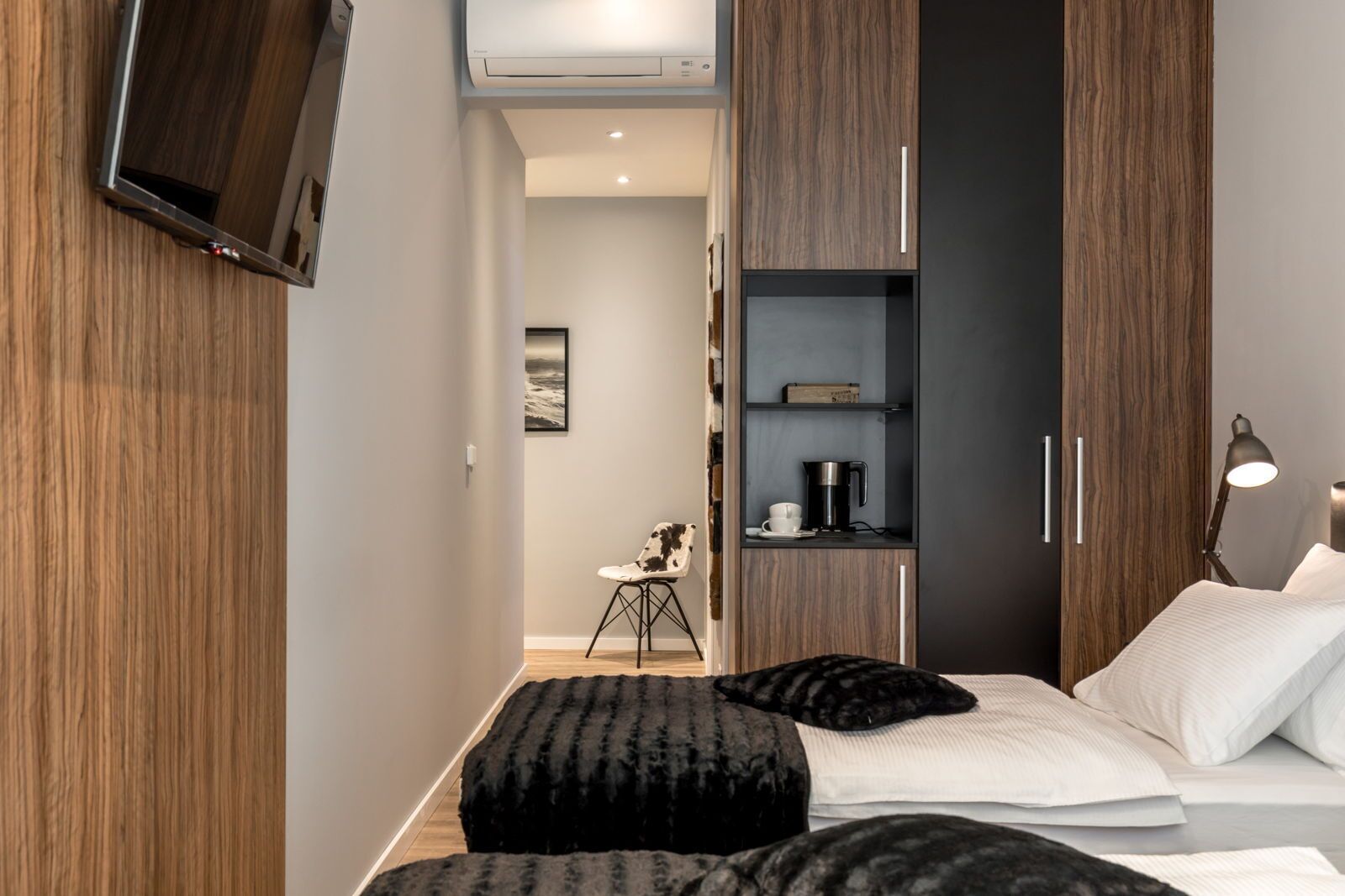 Une chambre moderne comprenant un lit, une table de chevet, une lampe et un petit coin cuisine.