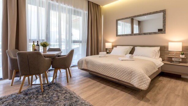 A hotel room with a bed, bedside tables, a desk with chairs, and a large window with curtains. - Luxury Apartment Marigold in Split (Split)