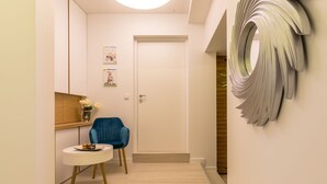 A hallway with a blue chair, a small round table, and a decorative wall piece. - Luxury Apartment Marigold in Split (Split)