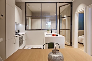 A modern kitchen with a central island, a built-in oven, and a large mirror above the sink. - Barcelona Plaza Catalunya Flat with Huge Terrace (Barcelona)