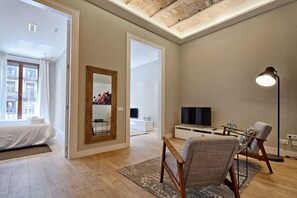 A modern hotel room with a bed, a seating area with a chair and table, a television, and a large mirror. - Barcelona Plaza Catalunya Flat with Huge Terrace (Barcelona)