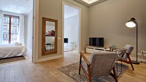 Un salon moderne avec un grand lit, un téléviseur, un canapé et une lampe sur pied.
