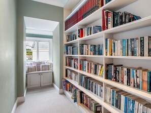Ett bibliotek med bokhyllor och en liten läshörna med en bänk.