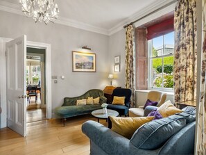 A living room with a sofa, armchairs, a coffee table, and a chandelier.
