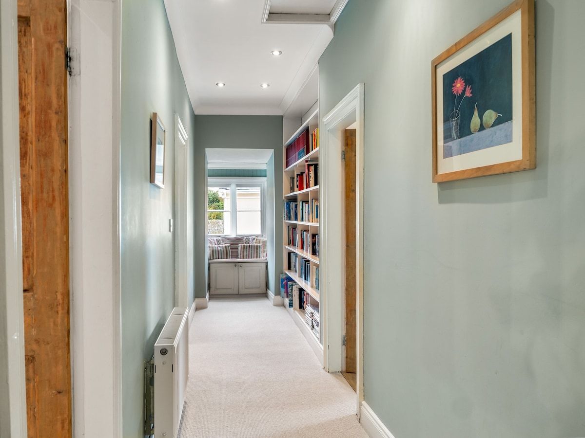 A hallway with a radiator, a window, and a bookshelf.