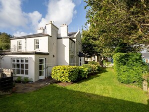 A two-story house with a well-maintained lawn and a hedge in the foreground.