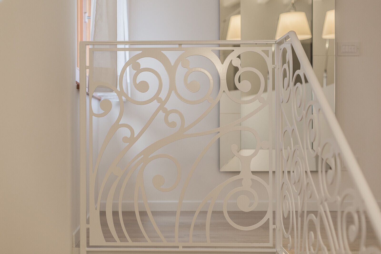 A white metal staircase railing with intricate designs.