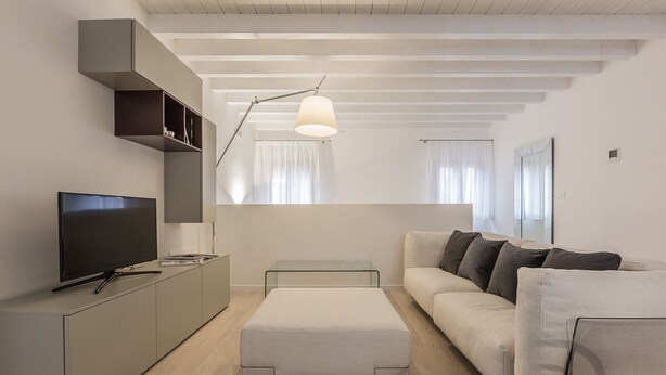 Un salon moderne doté d’un téléviseur à écran plat, d’un canapé, d’une table basse en verre et d’un design minimaliste.
