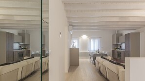 Une cuisine moderne dotée d’un îlot central, d’un coin repas avec une table et des chaises, et d’un mur miroir qui agrandit visuellement l’espace.