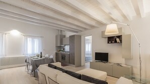 Un salon moderne comprenant un ensemble de canapés, un coin repas, une cuisine et un téléviseur.