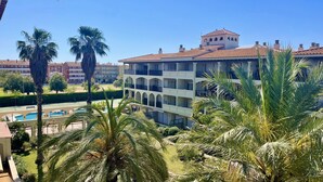 Un hotel de varios pisos con balcones, piscina y palmeras.