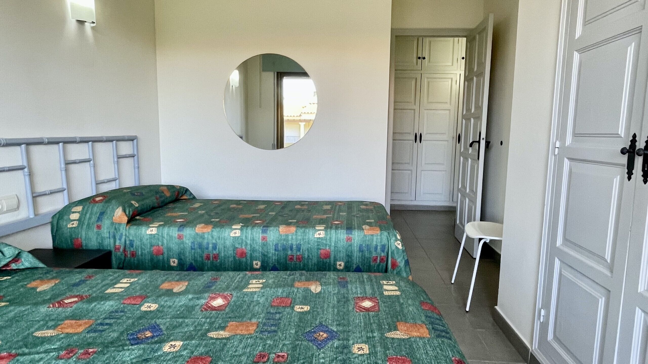 A bedroom with a bed, a mirror, a wardrobe, and a chair.