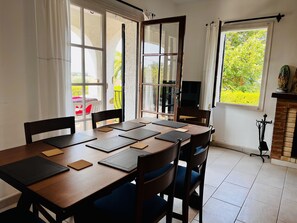 A dining area with a wooden table, chairs, and a view of greenery outside.
