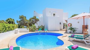 A pool area with lounge chairs and a white building in the background. - Villa Fort View - Four Bedroom Villa, Sleeps 8 (Santanyí)