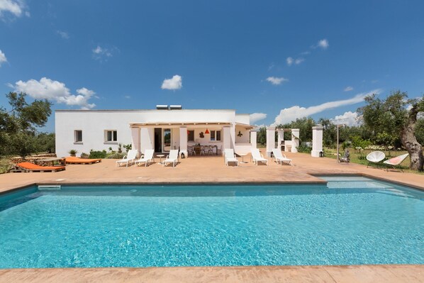 Ein modernes Haus mit Swimmingpool, Sitzgelegenheit im Freien und einer Terrassenfläche.