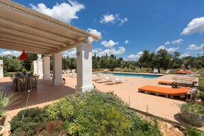 Un espace extérieur abrité comprenant une piscine, des chaises longues et une table avec des chaises.