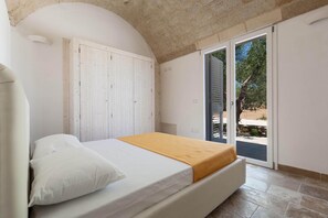 A bedroom with a bed, a white door, and a view of the outside. - La Serrazza by Perle di Puglia (Pescoluse Posto Vecchio)