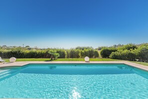 A rectangular swimming pool with clear blue water, surrounded by a well-maintained lawn and greenery. - La Serrazza by Perle di Puglia (Pescoluse Posto Vecchio)
