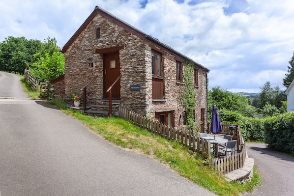 A stone building with a wooden door, a staircase, and a sign that reads 'The Canary.'
