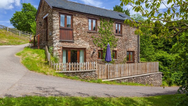 A stone house with a wooden fence, a paved driveway, and a clear sky. - The Granary, Luxborough (Luxborough)