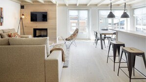 A modern living room with a sofa, a fireplace, a TV, and a dining area with stools. - Val de Ruda Luxe 52 by FeelFree Rentals (Baqueira)