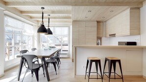 A modern kitchen with wooden cabinets, a central island with stools, and pendant lighting. - Val de Ruda Luxe 52 by FeelFree Rentals (Baqueira)