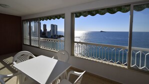 Ein Balkon mit weißem Tisch und Stühlen mit Blick auf eine Skyline und das Meer.