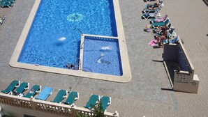 Ein großer rechteckiger Pool mit einem separaten Kinderbereich, umgeben von Liegestühlen und einem Rettungsschwimmerstand.