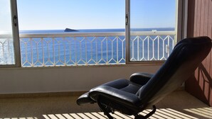 Ein Balkon mit Meerblick, ein schwarzer Stuhl und ein weißes Geländer.
