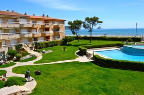 A well-maintained outdoor area with a swimming pool, a clear view of the sea, and a multi-story building with balconies.