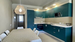 Una cocina moderna con armarios color turquesa, un microondas y una zona de comedor con mesa y sillas.